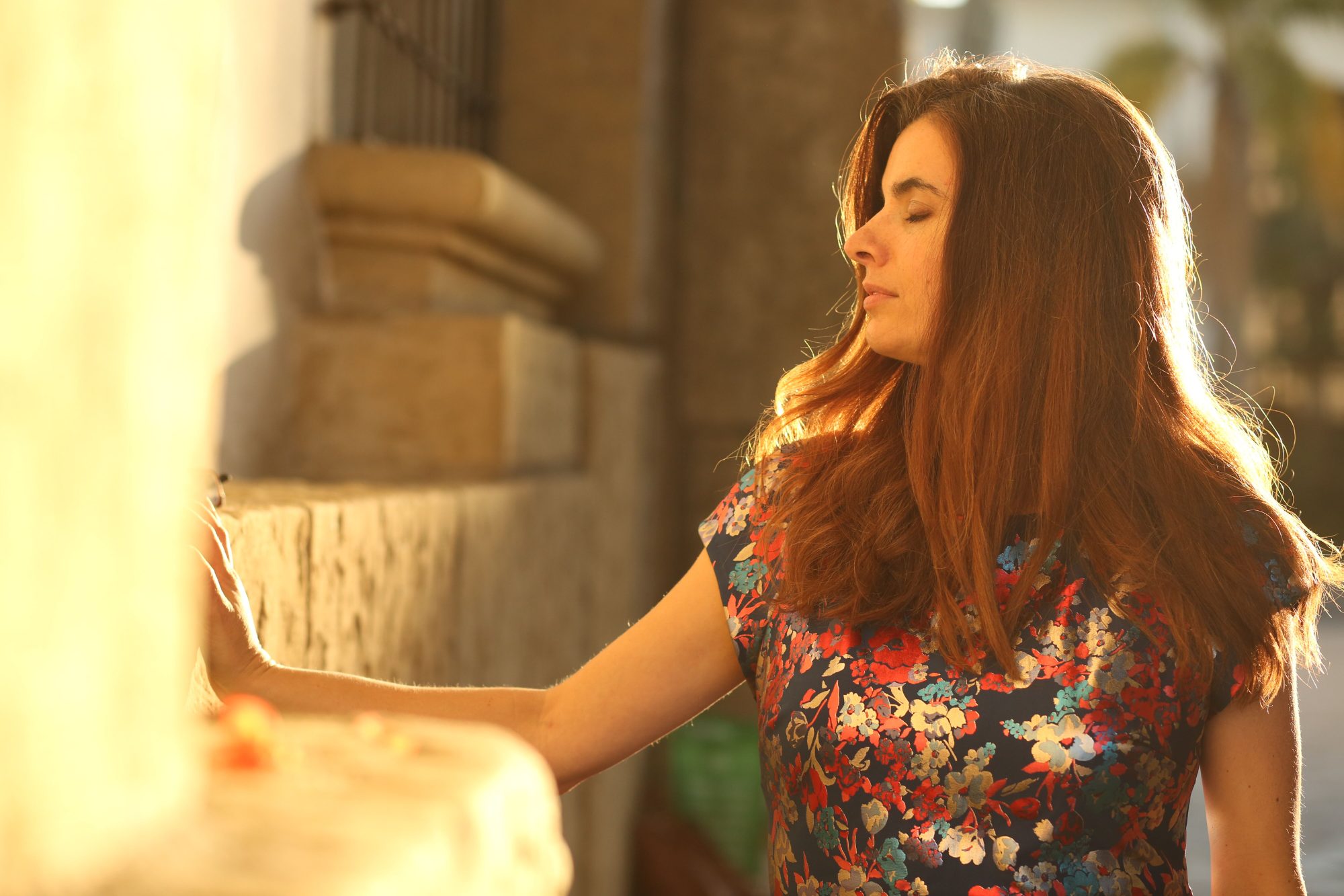 Lucinda Rae in golden light, eyes closed in prayer